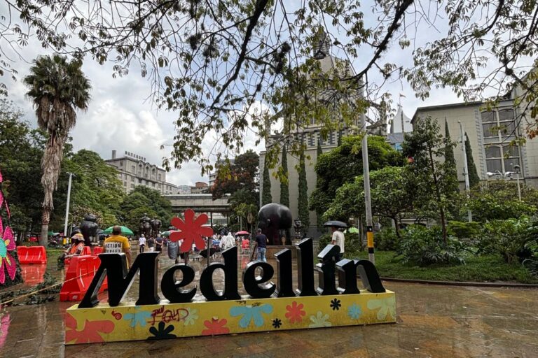 Colorful Medellín sign in Plaza Botero with Fernando Botero sculptures and the Museum of Antioquia in the background.