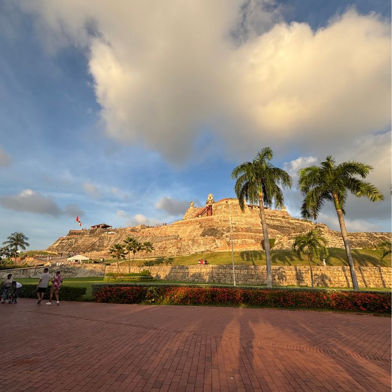 Golden hour view of Castillo San Felipe de Barajas fortress surrounded by palm trees in Cartagena.