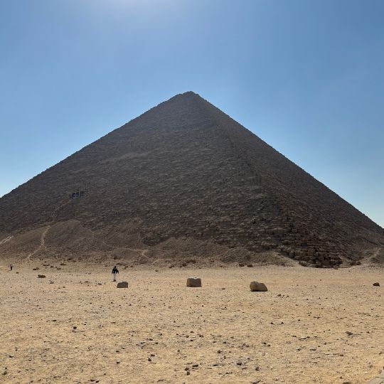 Close-up view of a pyramid in Giza with desert foreground and a clear blue sky overhead.