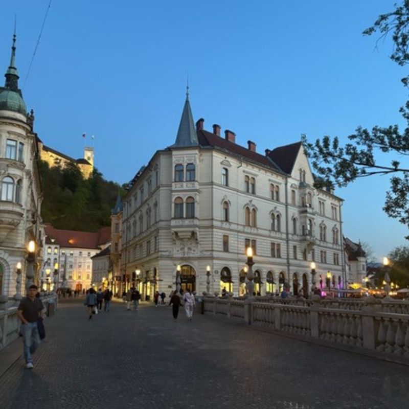 Evening view of historic Ljubljana, Slovenia, with pedestrians walking across a bridge in the city center.