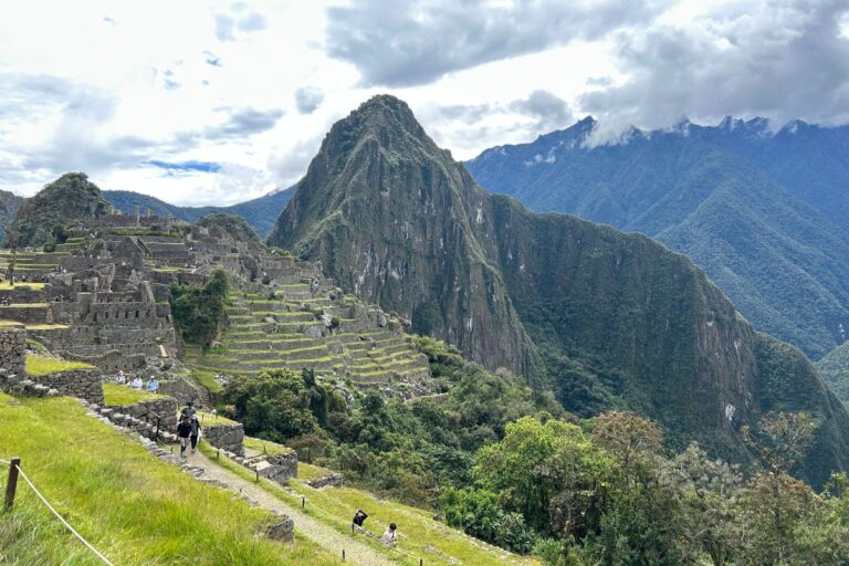 Panoramic view of Machu Picchu’s Inca ruins and green terraces with Huayna Picchu rising behind them.