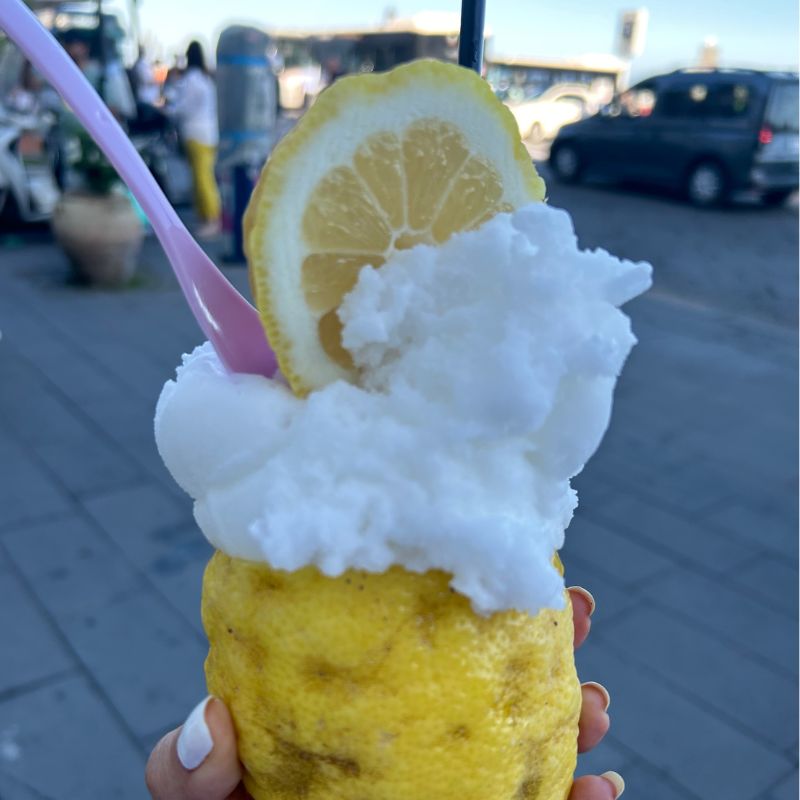 Fresh lemon granita served inside a hollowed-out Amalfi lemon and topped with a lemon slice along the waterfront.