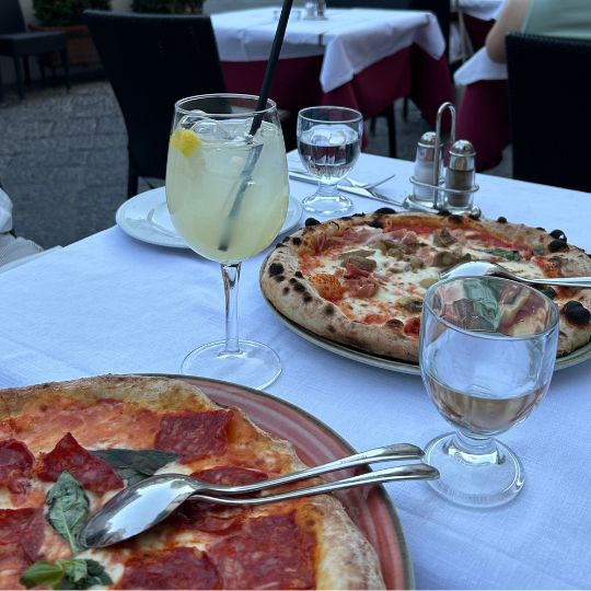 Outdoor dinner featuring Neapolitan-style pizza and a lemon cocktail at a restaurant on the Amalfi Coast.