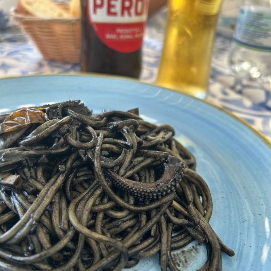 Plate of squid ink pasta with seafood served at a restaurant along Italy's Amalfi Coast.