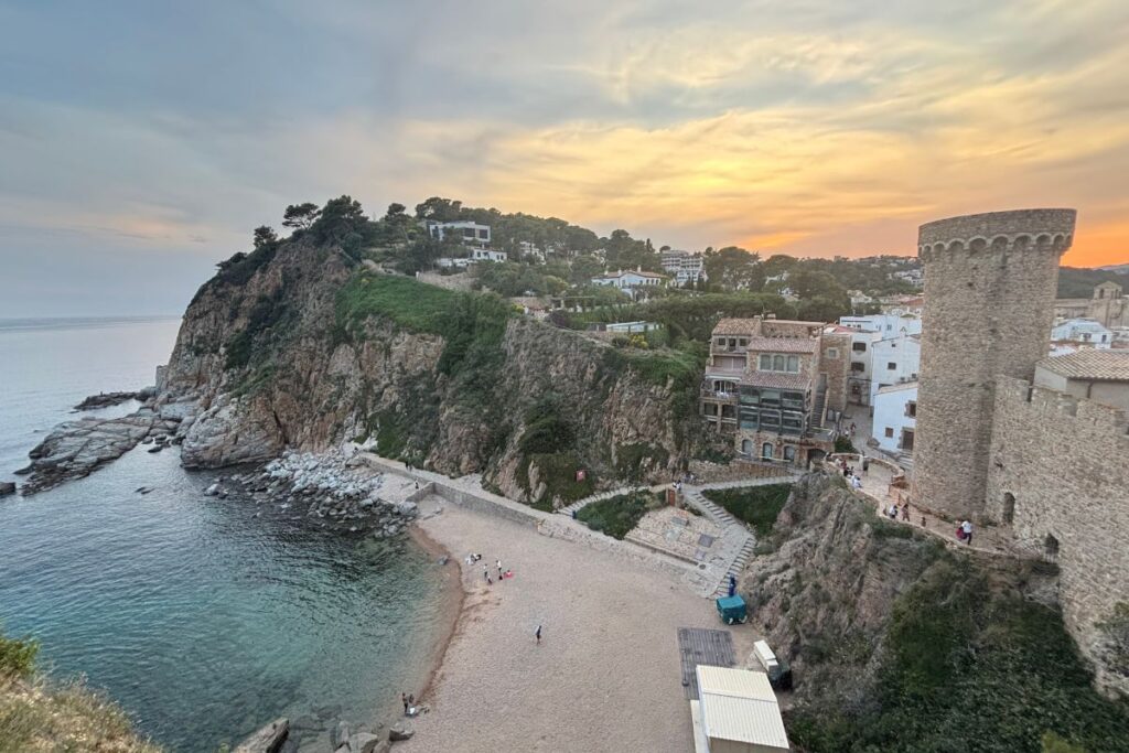 Sunset view of the medieval walls and beach in Tossa de Mar on Spain's Costa Brava
