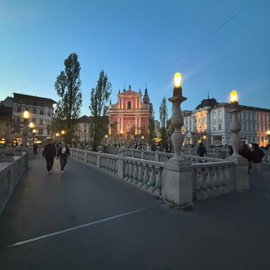 Ljubljana's Triple Bridge illuminated at dusk near Prešeren Square.