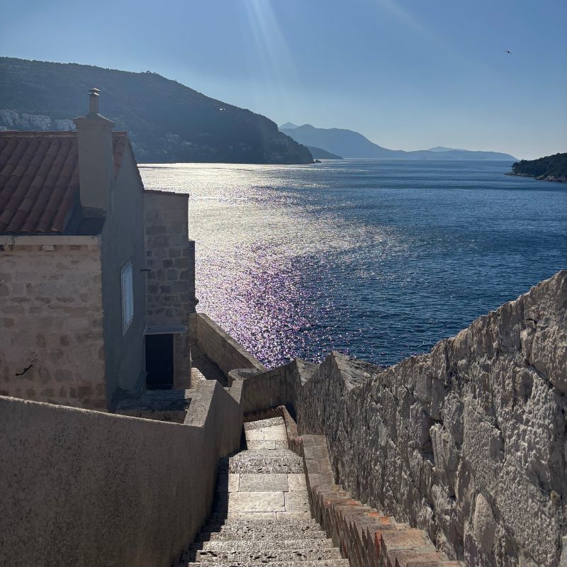 Stone staircase descending from Dubrovnik's city walls toward the Adriatic Sea.