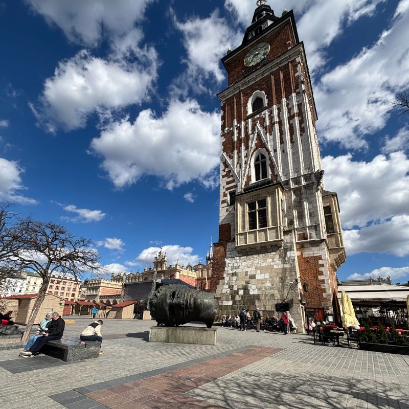 The Town Hall Tower rising above Kraków's Main Market Square under a bright spring sky.