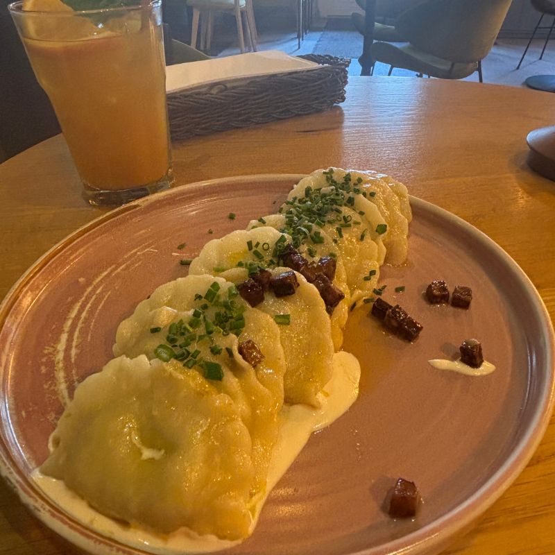 Traditional pierogi topped with chives and sauce at a restaurant in Kraków.