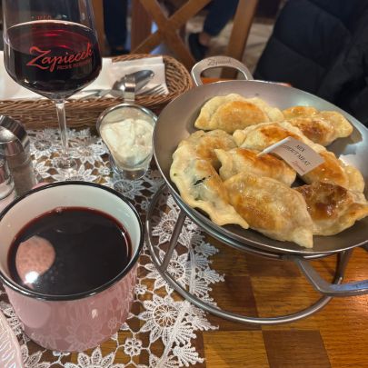 Traditional Polish meal featuring pierogi served with sauces alongside a warm drink in a cozy Kraków restaurant.