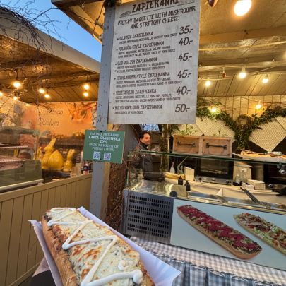 Traditional food stall in Kraków serving zapiekanki, Poland's popular open-faced baguette sandwiches, with menu boards and fresh preparations on display.