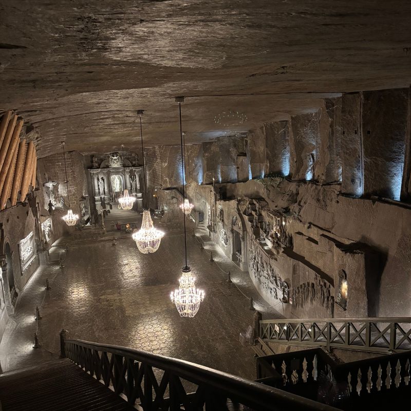 Vast underground chapel carved entirely from salt, illuminated by chandeliers and featuring detailed sculptures and reliefs.