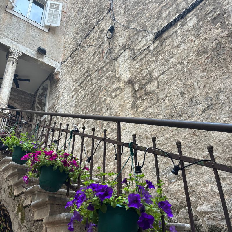 Colorful flower pots hanging along a stone staircase in Split's Old Town, showcasing the charming details and hidden corners discovered while wandering Central Europe.