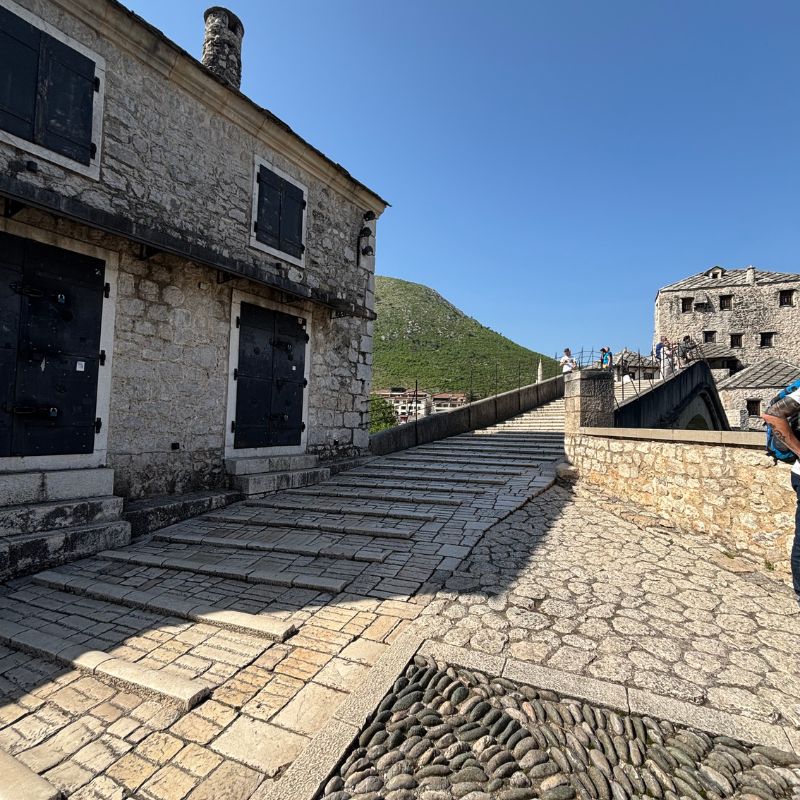 Stone walkway leading onto Stari Most bridge in Mostar's historic old town.