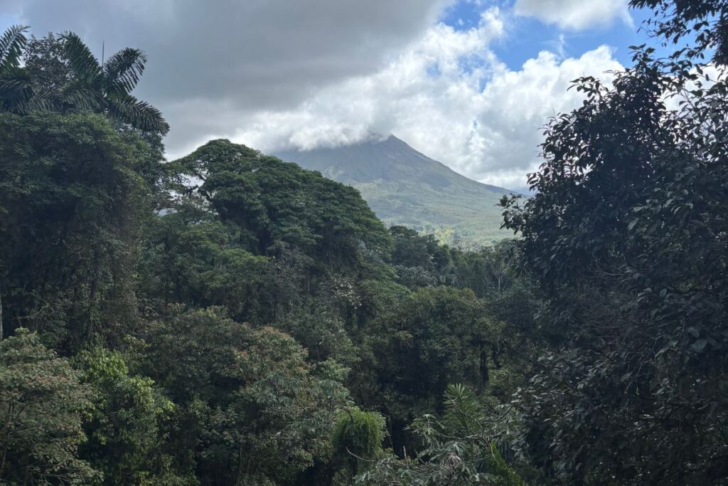 View of Arenal Volcano rising above the Costa Rican rainforest beneath dramatic clouds near La Fortuna.