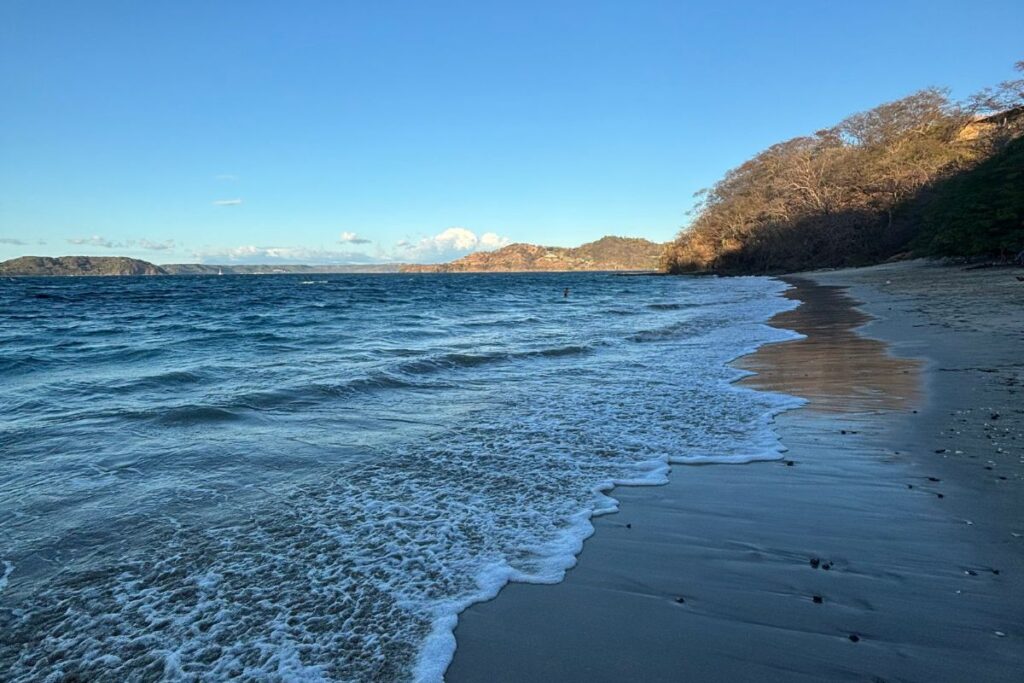 Quiet beach along Costa Rica's Pacific coast with gentle waves at sunset.