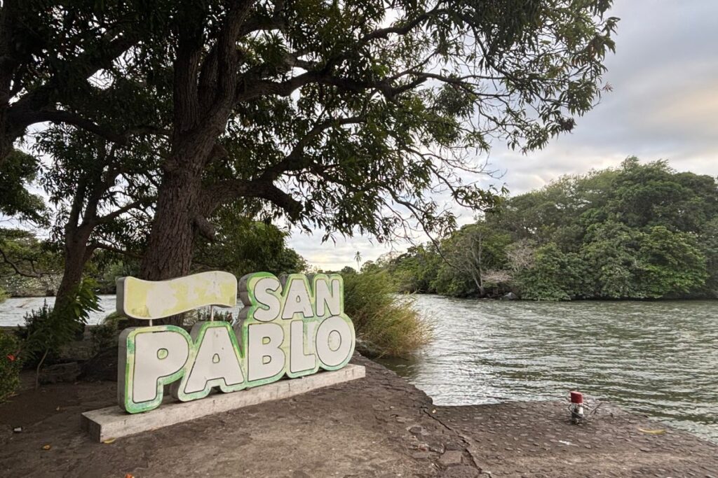 San Pablo sign beside the water at the historic San Pablo Fortress in Granada, Nicaragua, surrounded by lush trees and the shoreline.