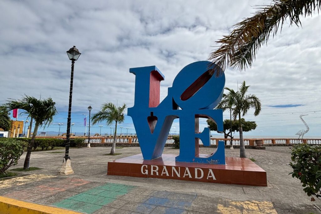 Colorful LOVE Granada sign overlooking Lake Nicaragua along Granada's lakeside promenade with palm trees and blue skies.