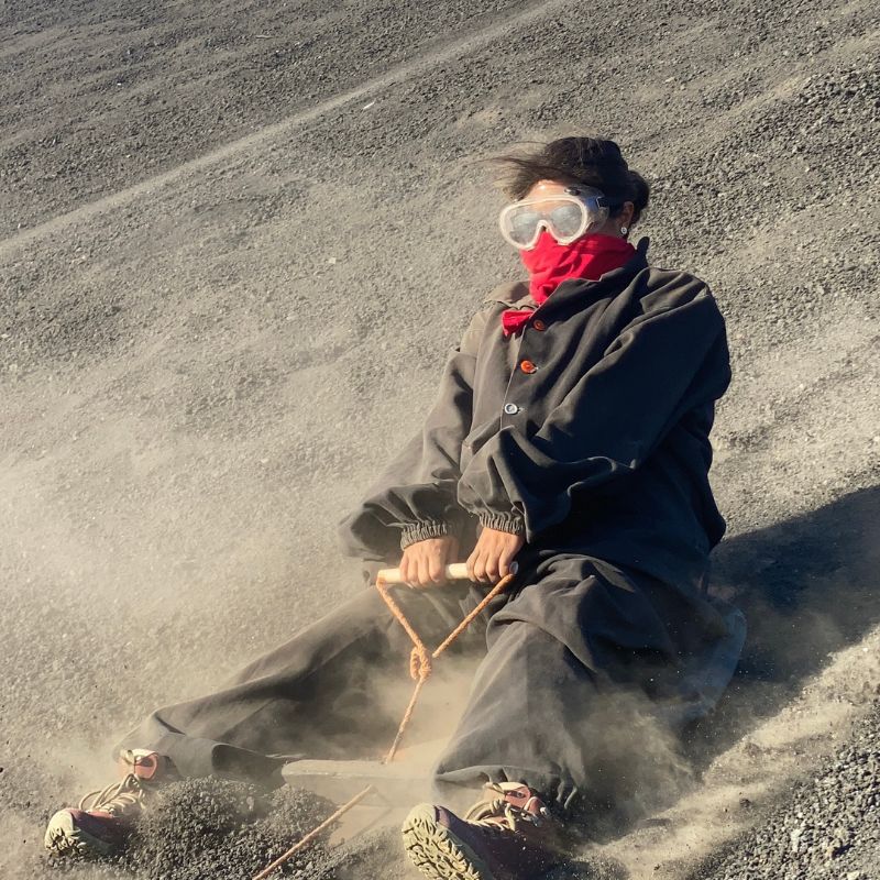 Traveler wearing protective goggles and coveralls volcano boarding down the ash-covered slopes of Cerro Negro Volcano in Nicaragua.