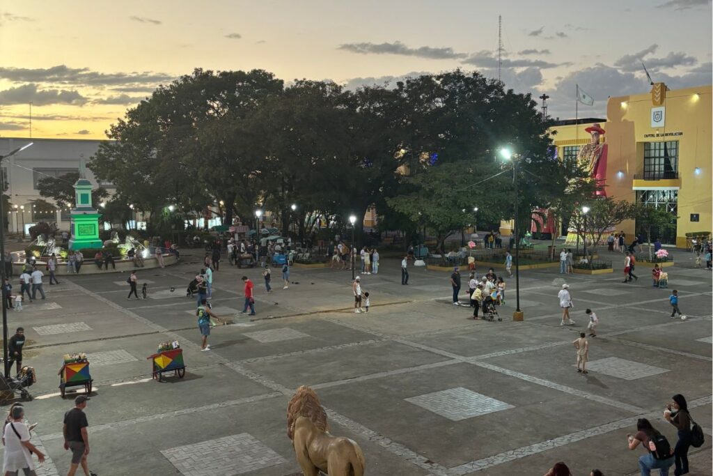 Evening view of León's central plaza filled with families, street vendors, and locals gathering at sunset in Nicaragua.
