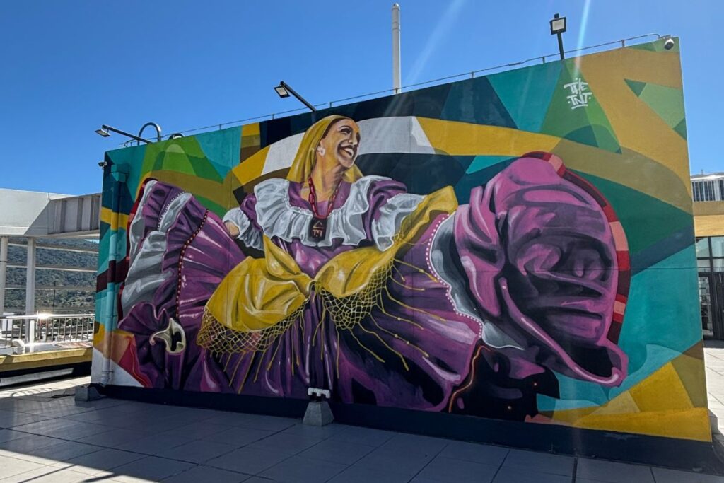 Large colorful mural depicting a traditional folkloric dancer painted on the side of a building in downtown San Salvador, El Salvador.