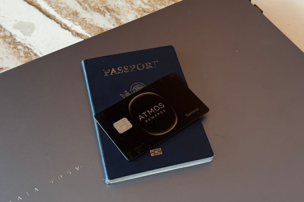 Atmos Rewards Summit card resting on a U.S. passport atop a laptop, representing travel rewards and points earning.