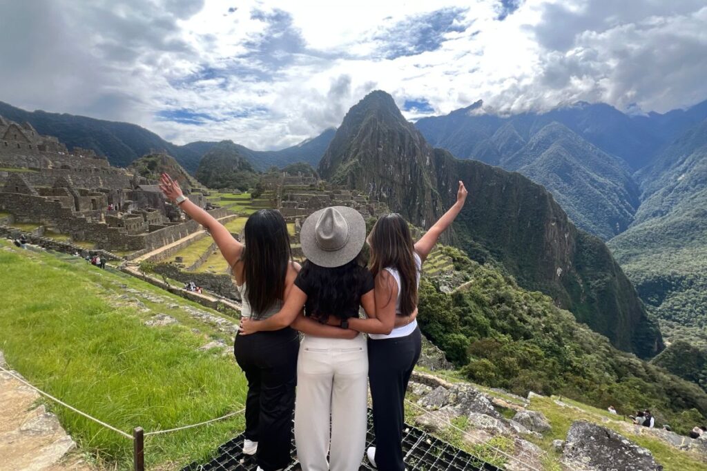 Three travelers overlooking Machu Picchu and the surrounding mountains in Peru
