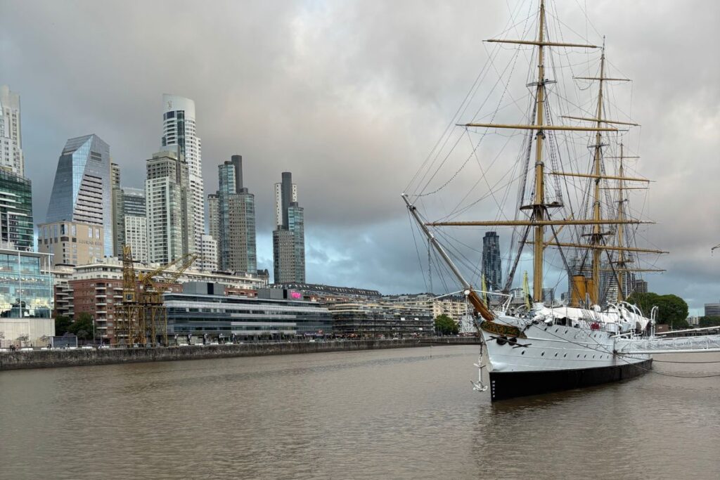 Historic sailing ship docked in Puerto Madero with the Buenos Aires skyline in the background.