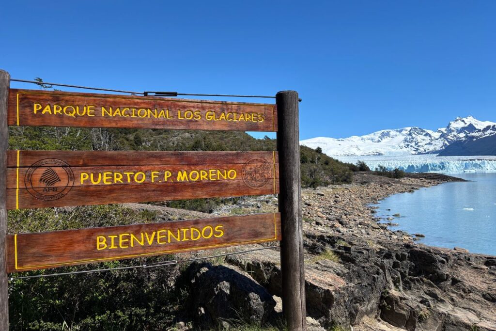 Entrance sign for Los Glaciares National Park with Perito Moreno Glacier in the background near El Calafate, Argentina