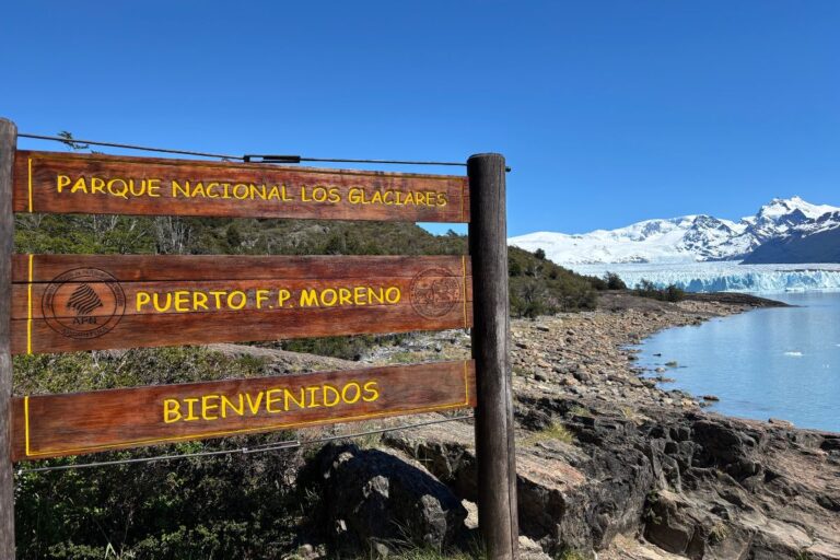 Entrance sign for Los Glaciares National Park with Perito Moreno Glacier in the background near El Calafate, Argentina