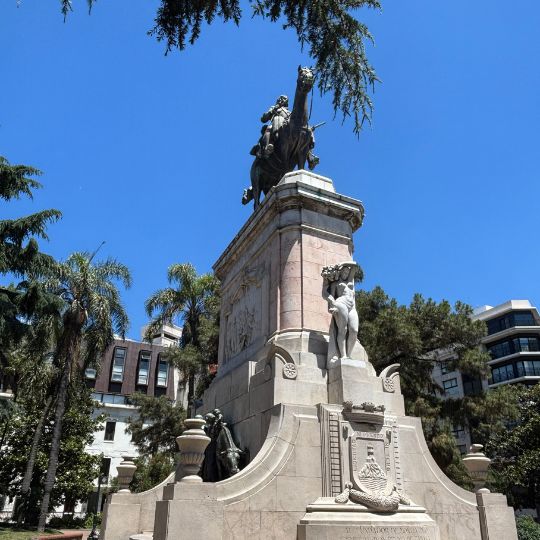 Equestrian monument in Montevideo surrounded by palm trees and historic architecture on a sunny afternoon.