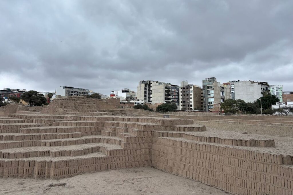 Ancient adobe ruins of Huaca Pucllana surrounded by modern apartment buildings in Miraflores, Lima