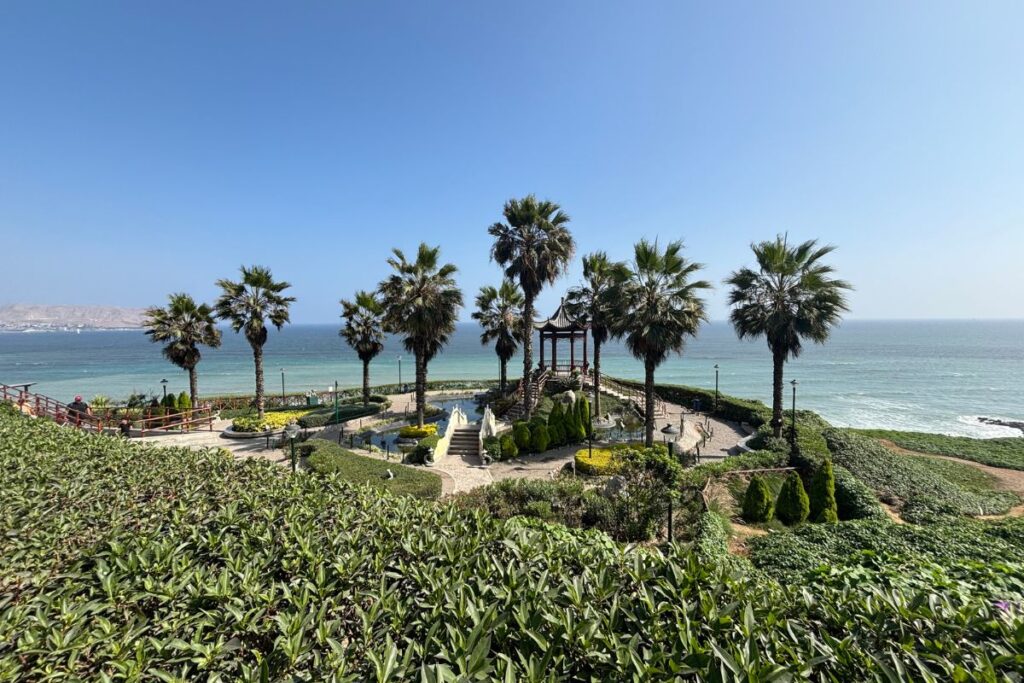 Parque Chino de Miraflores with palm trees, landscaped gardens, and the Pacific Ocean